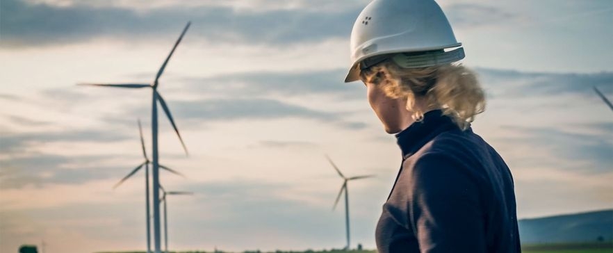 Die Zukunft ist grün. Frau vor Windrädern.