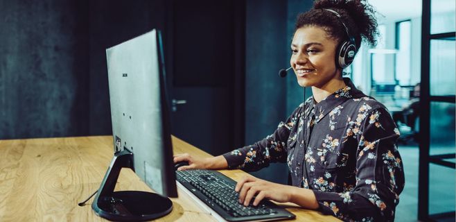 Junge Dame mit Headset arbeitet an einem PC