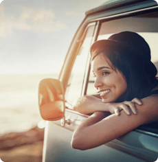 Frau steht mit einem Bulli am Meer