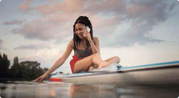 Junge Frau mit Handy auf einem Surfbrett