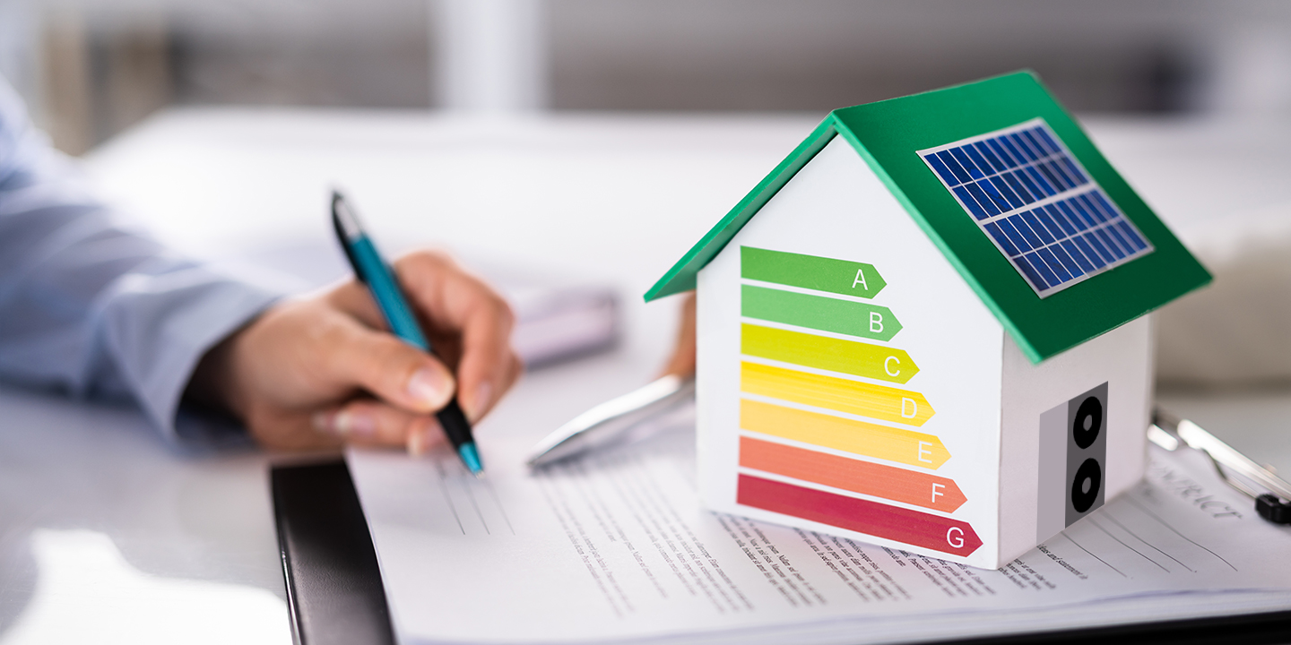 Ein Modellhaus mit Energieeffizienz-Skala und Solarpanel steht auf einem Vertragswerk
