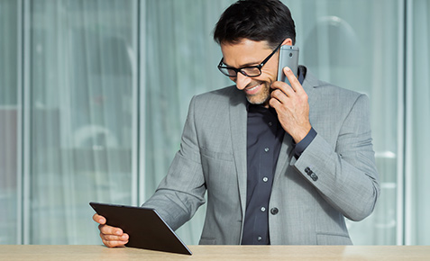 Mann am Telefon und Tablet in einer Webkonferenz mit Vodafone Conderencing