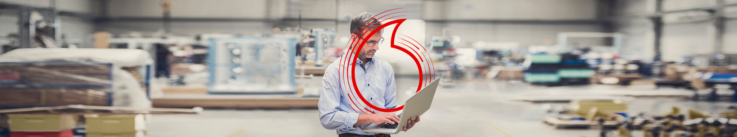 Mann in einer Firmenhalle steuert mit seinem Laptop Prozesse &uuml;ber die Cloud.