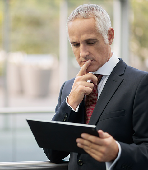 Gesch&auml;ftsmann im Anzug blickt nachdenklich auf sein Tablet