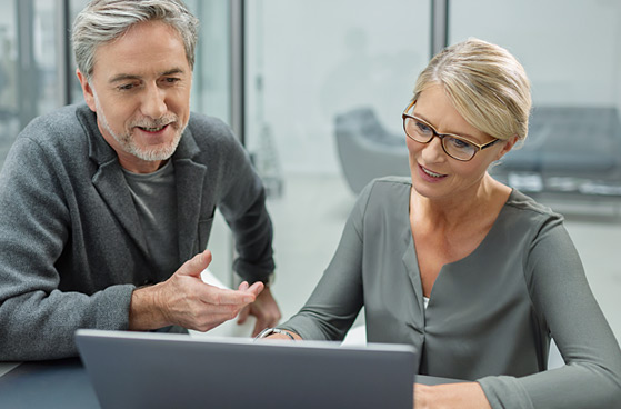 Ein Mann und eine Frau gucken zusammen auf den Laptop.