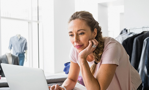 Modeverk&auml;uferin steht im Laden und bedient den Laptop