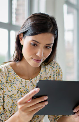 Eine junge Frau sitzt im B&uuml;ro mit hohen Decken und surft auf ihrem Business-Tablet im Internet, um mehr Datenvolumen zu buchen.