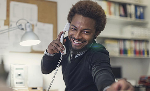 Mann mit Telefonh&ouml;rer am Arbeitsplatz.
