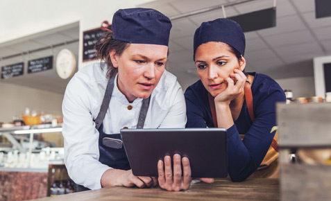 Gastronominnen vor Tablet im Cafe