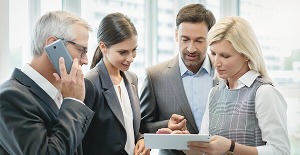 Zwei Damen und zwei Herren besprechen Gesch&auml;ftliches mit Hilfe eines Tablets