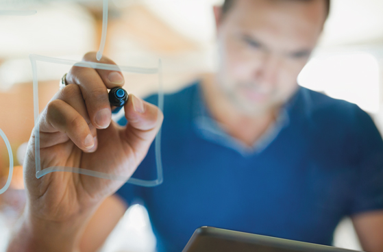 Mann schreibt L&ouml;sungs-Ideen auf eine Scheibe. 