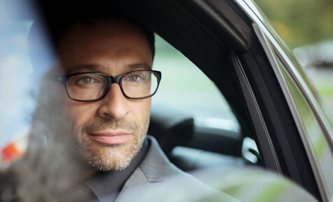 Business-Mann sitzt im Auto und nutzt f&uuml;r sein Unternehmen die M&ouml;glichkeiten des Internet of Things. In seinem Unternehmen gibt es untereinander vernetzte Maschinen.