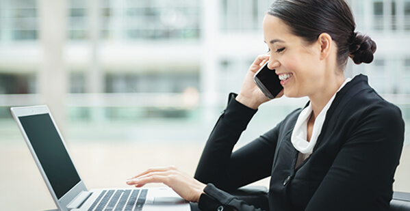 Eine Dame telefoniert, w&auml;hrend sie am Laptop arbeitet
