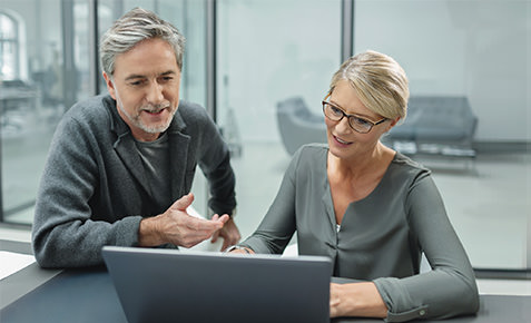 Zwei Arbeitskollegen am Laptop in einer Webkonferenz.