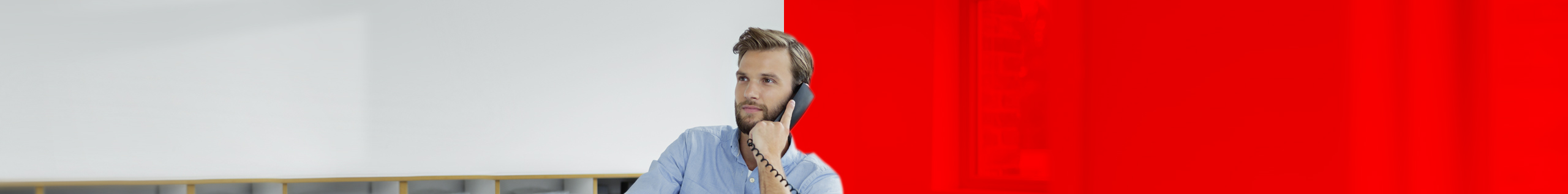 Mann sitzt am Computer und telefoniert.