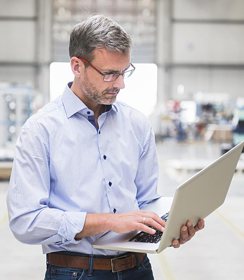 Ein Mitarbeiter in der Halle am Laptop.