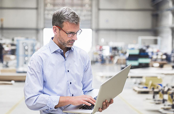 Ein Mitarbeiter in der Halle am Laptop.