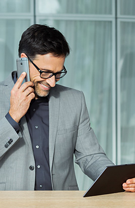 Mann telefoniert und guckt auf sein Tablet.