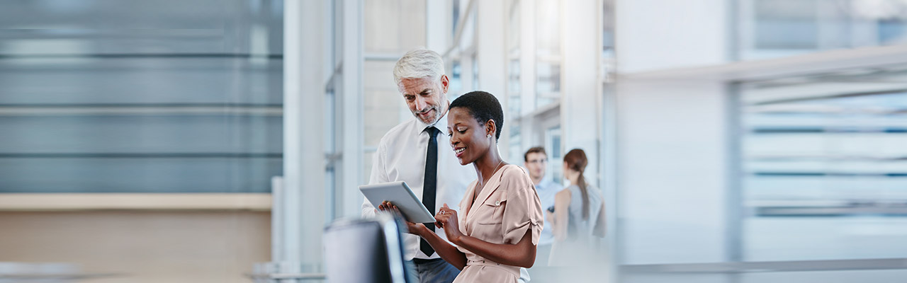 Junge Dame und &auml;lterer Herr mit Krawatte betrachten etwas auf einem Tablet