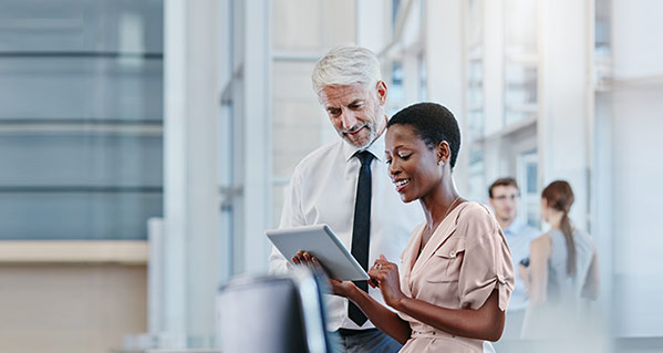 Junge Dame und &auml;lterer Herr mit Krawatte betrachten etwas auf einem Tablet