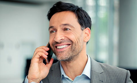 Ein Gesch&auml;ftsmann mit Smartphone in der Hand  geht aus dem Unternehmen. Er hat ein Ready Business und ist Bereit f&uuml;r die kommenden Aufgaben und Herausforderungen der Digitalisierung.