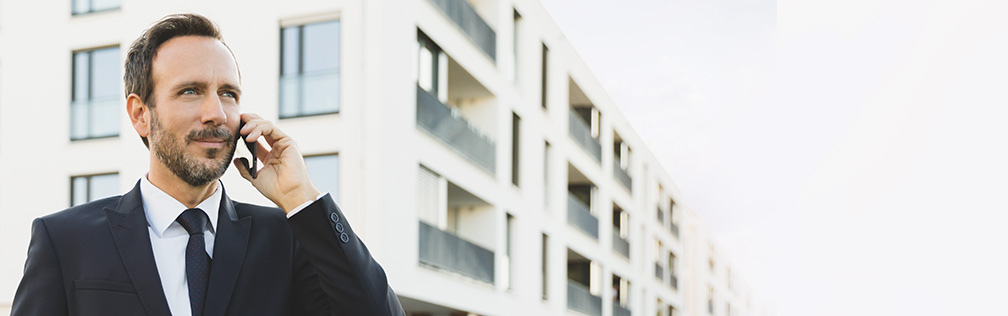 Ein Business-Mann steht am Fenster und schaut heraus. Er geh&ouml;rt zu Vodafones Business-Referenzkunden.