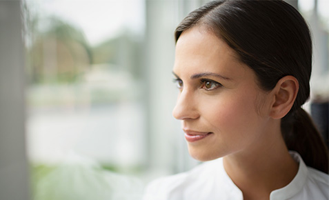 Eine Business-Frau auf Gesch&auml;ftsreise, schaut aus dem Fenster und nutzt w&auml;hrend der Reise spezielle Auslandsoptionen f&uuml;rs Tablet.