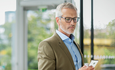 Gesch&auml;ftsmann an einem Business-Standort liest auf Handy