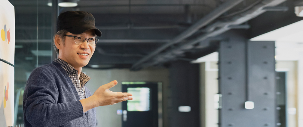 Mann pr&auml;sentiert vor einem gro&szlig;en Whiteboard.