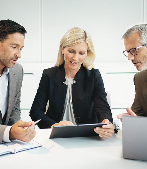 Eine Dame mit Tablet und zwei Herren bei einer Besprechung