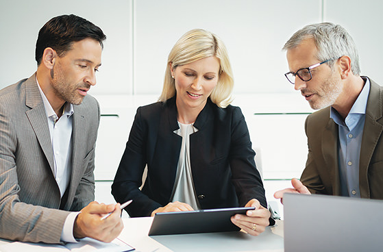 Eine Dame mit Tablet und zwei Herren bei einer Besprechung