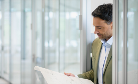Mann im B&uuml;ro schaut auf einen Plan