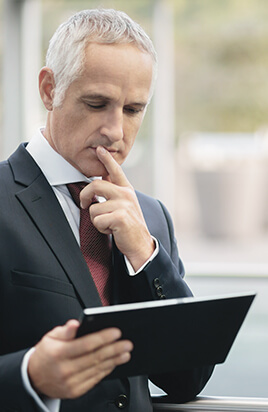 Gesch&auml;ftsmann pr&uuml;ft telematikbasierte Versicherungen auf Tablet