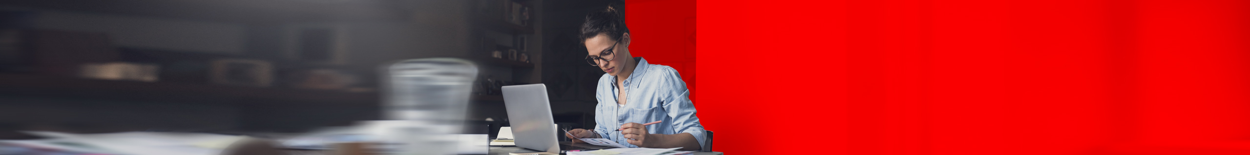 Frau sitzt am Schreibtisch und sortiert ihre Vertragsdokumente.