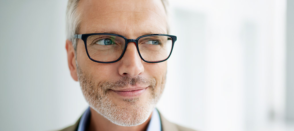 Grauhaariger Mann mit Brille schaut in Nahaufnahme zur Seite.