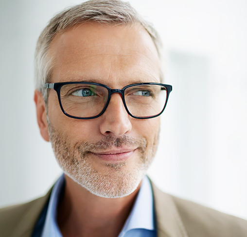 Grauhaariger Mann mit Brille schaut in Nahaufnahme zur Seite.