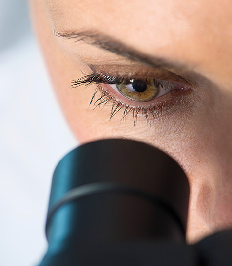 Frau schaut durch Mikroskop