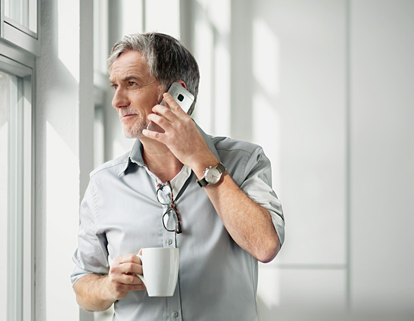 Ein Mann mit Tasse in der Hand telefoniert &uuml;ber WiFi Calling von Vodafone.