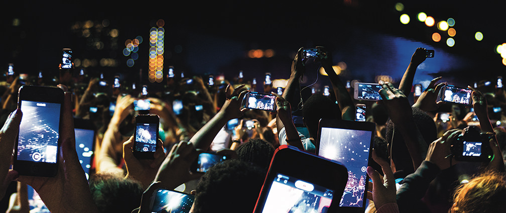 Menschen bei einem Konzert halten ihr Smartphone in die H&ouml;he