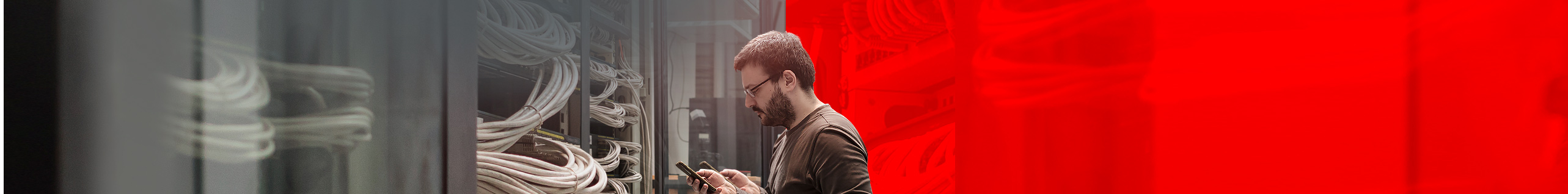 Mann steht mit einem Handy im Server-Raum