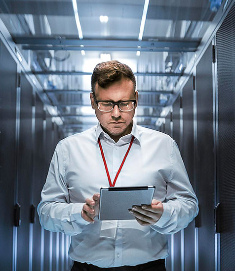 Mann steht mit Tablet neben Servern