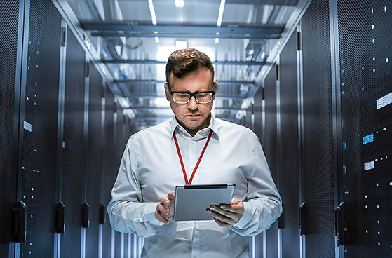 Mann steht mit Tablet neben Servern