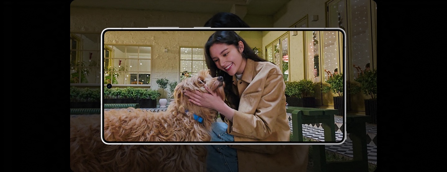 In einem Video ist eine Frau zu sehen, die abends mit ihrem Hund spazieren geht. Der Hund rennt auf die Frau zu. Dank der Kamera des Galaxy S25 Ultra ist die Bildqualit�t scharf und klar.